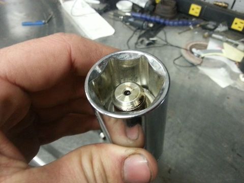 1995 Ford F-150 - A hand holds a socket wrench, revealing a part within its hexagonal opening.