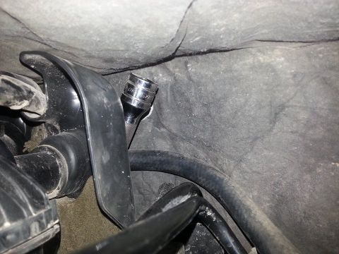 1995 Ford F-150 - A close-up view of a socket wrench positioned near a hose within a vehicle's engine compartment.