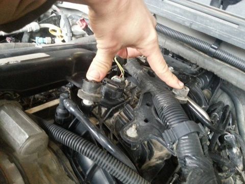1995 Ford F-150 - A hand manipulates electrical connectors and wiring within a vehicle's engine bay.
