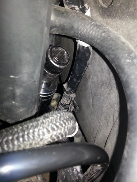 1995 Ford F-150 - A socket wrench is being used to access a component within the engine bay, surrounded by hoses and wiring.