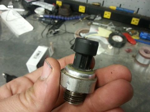 1995 Ford F-150 - A hand holds an automotive sensor part, likely for a vehicle's engine or transmission.