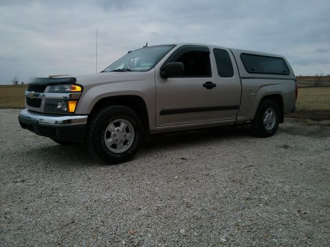 1986 Ford Bronco - Side view of a silver Chevrolet Colorado pickup truck equipped with an aftermarket camper shell.