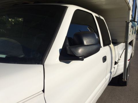 1997 Dodge 3500 - This white pickup truck appears to be from the late 1990s, with a camper shell mounted in the bed.