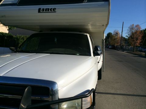 1997 Dodge 3500 - White pickup truck with a Lance camper shell parked on a residential street.