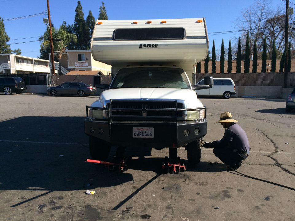 Front view of a 1997 Dodge 3500 with a Lance camper, jacked up for service