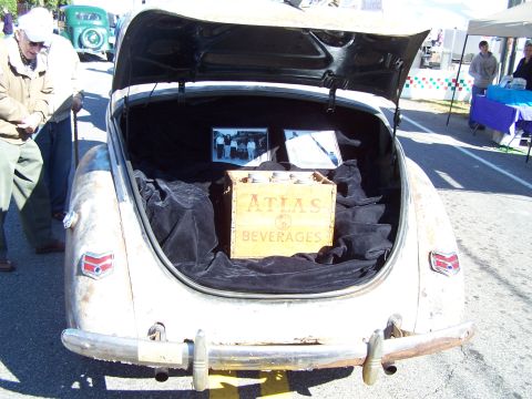 1971 Ford Ranchero - Trunk of a classic car displays a crate of Atlas Beverages and old photographs, with another vehicle in the background.