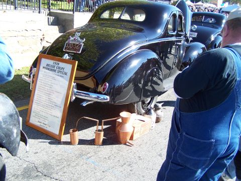 1971 Ford Ranchero - 1939 Deluxe Coupe Moonshine Special on display with informational board and distilling apparatus.