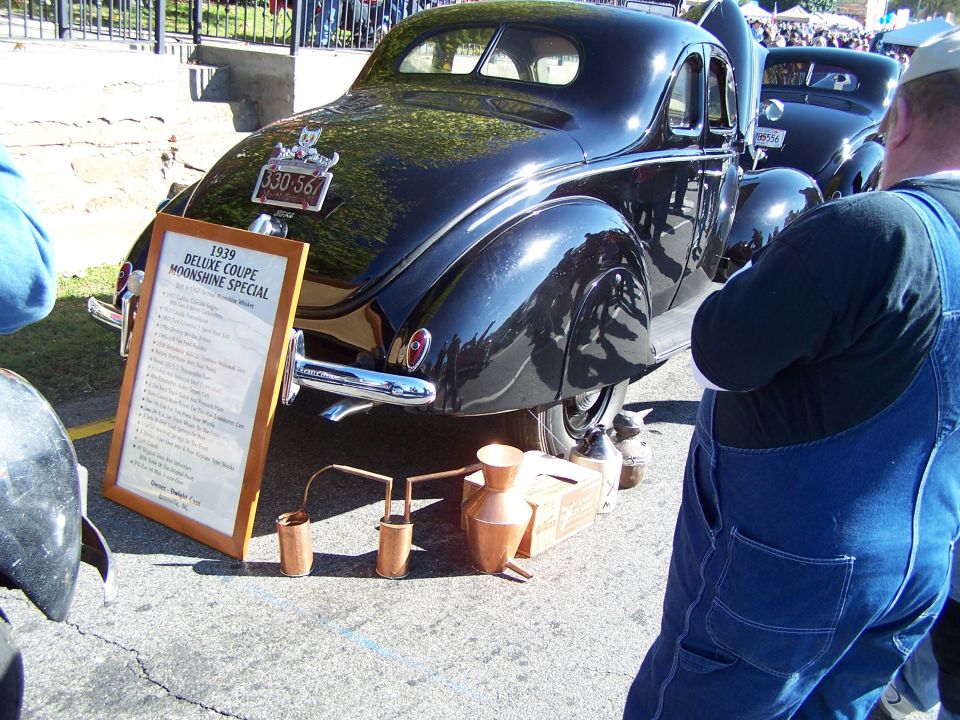 1939 Deluxe Coupe Moonshine Special car, rear view, with display board and copper distilling equipment