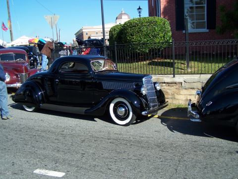 1971 Ford Ranchero - A black coupe from the mid-1930s is parked next to another vehicle on a sunny day.