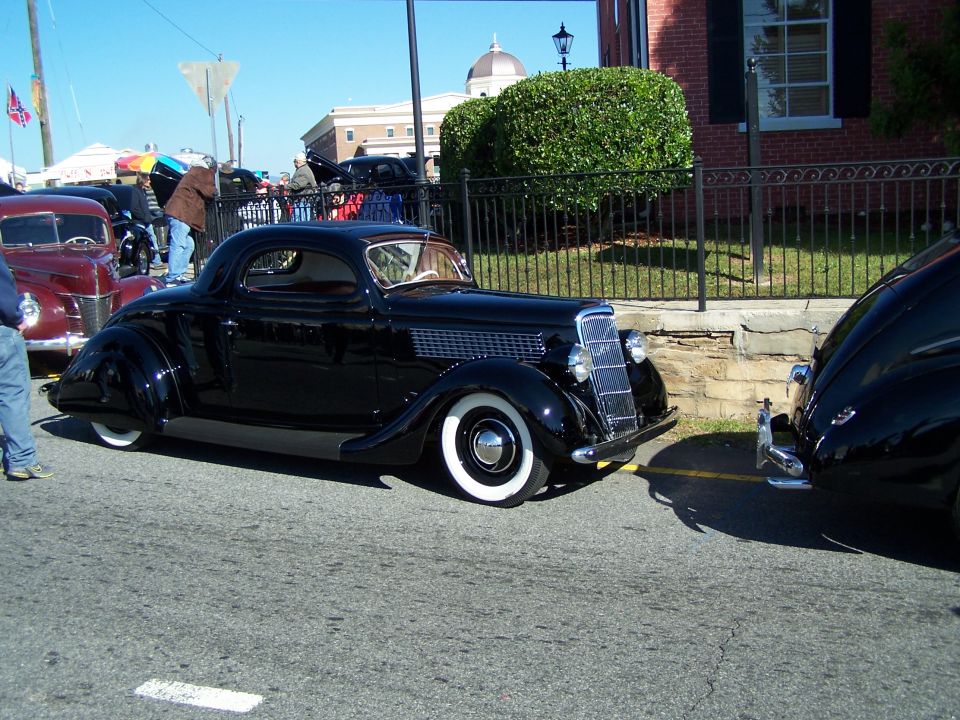 Black 1935 coupe with chrome grille and whitewall tires parked on asphalt