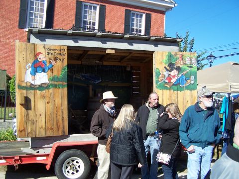 1971 Ford Ranchero - A trailer with rustic wooden doors painted with cartoon figures and text is displayed outdoors with people gathered around.