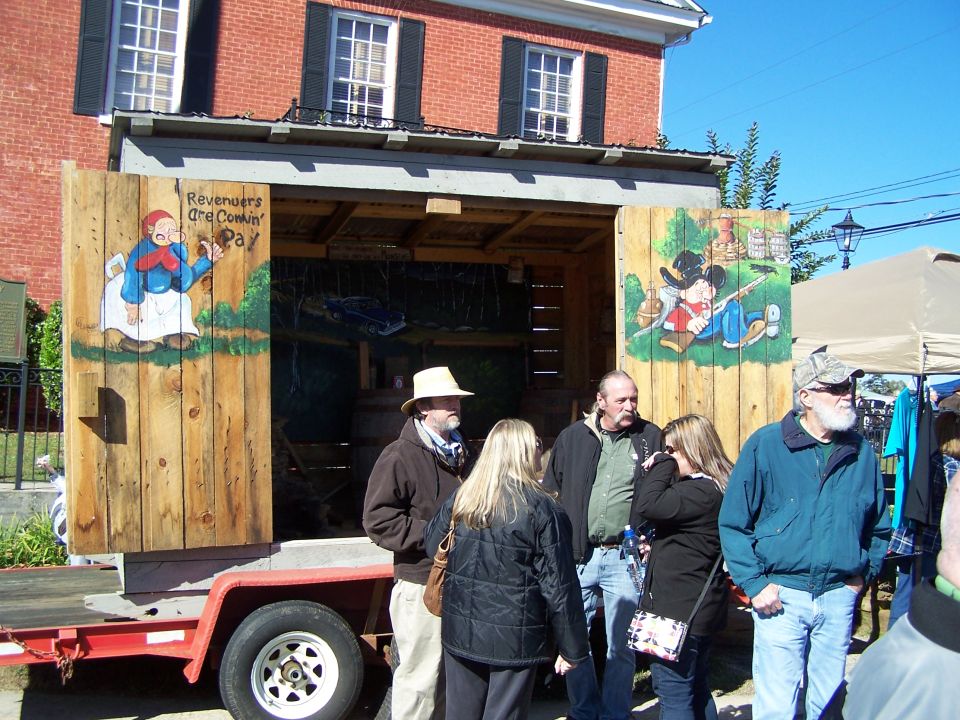 Wooden trailer with painted doors depicting cartoon characters and text, with people standing in front