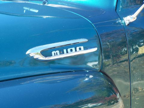 1971 Ford Ranchero - A chrome "F-100" emblem is visible on the side of a teal-colored vehicle.