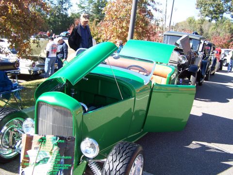 1971 Ford Ranchero - A line of vehicles, including a green hot rod, are displayed outdoors at an event.