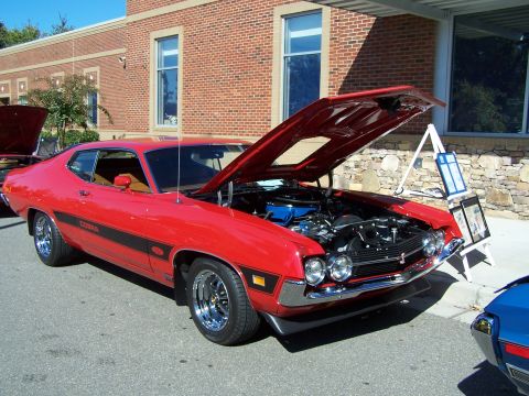 1971 Ford Ranchero - A red muscle car with a black stripe and 'Cobra' text is displayed with its hood open, revealing the engine bay.