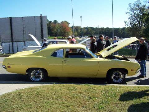 1971 Ford Ranchero - A yellow 1970 Ford Falcon is displayed with its hood open, drawing attention from onlookers.
