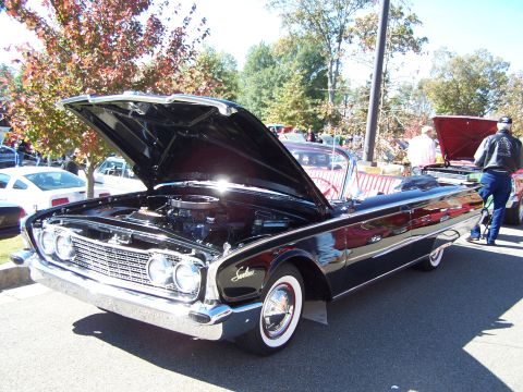 1971 Ford Ranchero - A black convertible with its hood open, revealing the engine. The vehicle has whitewall tires and is seen at an outdoor event.