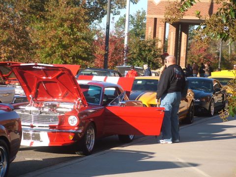 1971 Ford Ranchero - A bright red 1965 Ford Mustang is displayed with its hood and driver's door open at an outdoor car show.