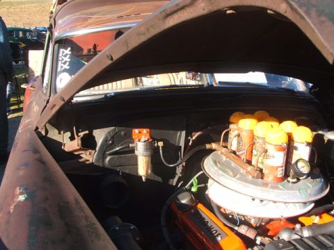 1971 Ford Ranchero - The engine bay of a classic car is open, revealing a V8 engine with custom modifications and several canisters.