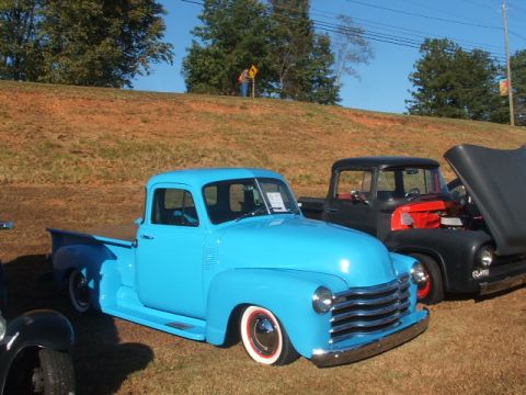 1971 Ford Ranchero - A bright blue pickup truck is parked next to a black truck with its hood open.