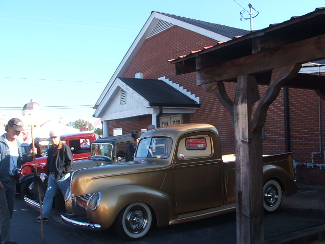 Gold pickup truck with whitewall tires, seen from the front-right