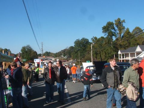 1971 Ford Ranchero - A crowd gathers around a classic black car with its hood open at an outdoor event, likely a car show.