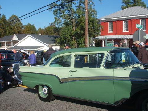 1971 Ford Ranchero - A two-tone green sedan is parked at an outdoor gathering with other vehicles and people.