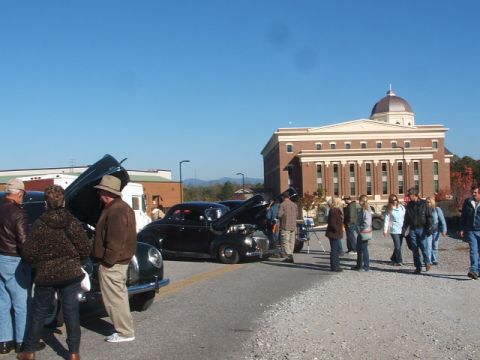 1971 Ford Ranchero - Several classic cars are on display outdoors with a large brick building in the background.