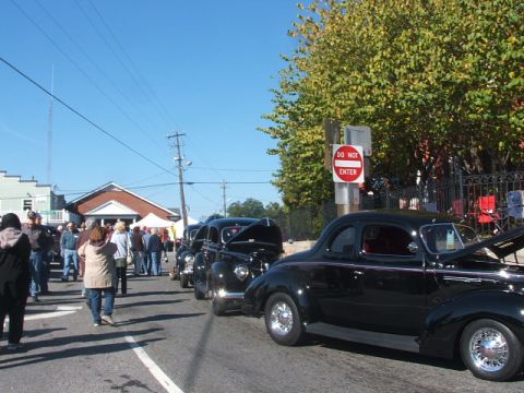1971 Ford Ranchero - Classic cars are lined up on a street, with people gathered around them at an outdoor event.