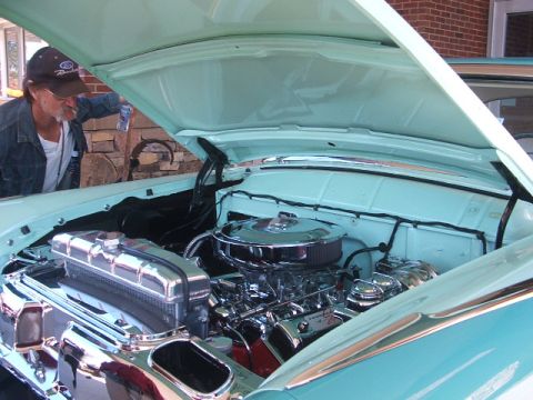 1971 Ford Ranchero - A man inspects the polished engine of a vintage automobile, with the hood open.