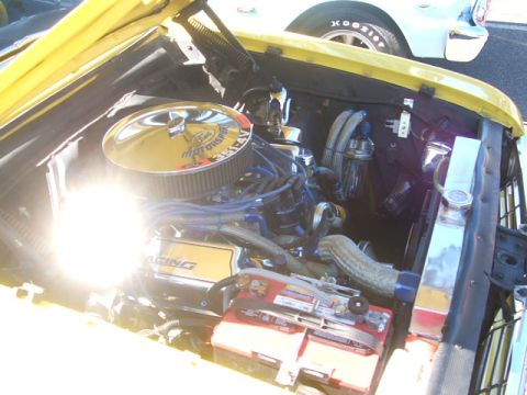 1971 Ford Ranchero - Engine bay details of a yellow vehicle, with a glimpse of another car in the background.