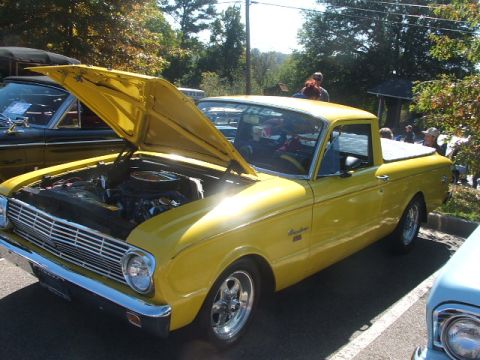 1971 Ford Ranchero - A yellow pickup truck is parked outside with its hood up, revealing the engine compartment.