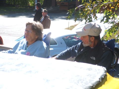 1971 Ford Ranchero - A white car with a unique side profile is visible behind two people seated in chairs.