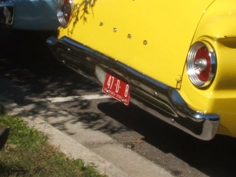 1971 Ford Ranchero - A close-up view of the rear of a yellow vehicle, a chrome bumper and a red license plate.