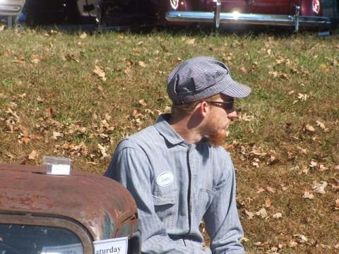 1971 Ford Ranchero - A man in work attire sits outdoors near a rusty vehicle part, with another car visible in the background.