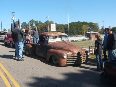 1971 Ford Ranchero - A heavily rusted pickup truck with custom green wheels is displayed at an outdoor event.
