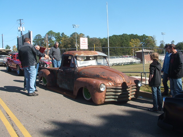 Rusty pickup truck with green wheels, front grille visible