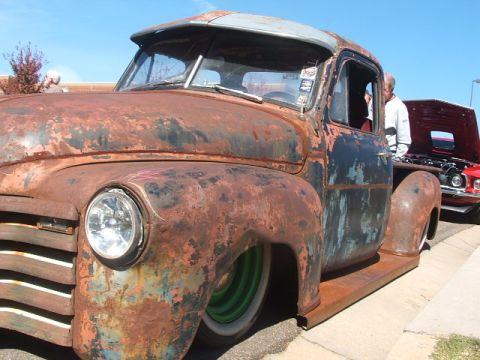 1971 Ford Ranchero - This heavily rusted pickup truck features a visor and green wheels, with another vehicle visible in the background.