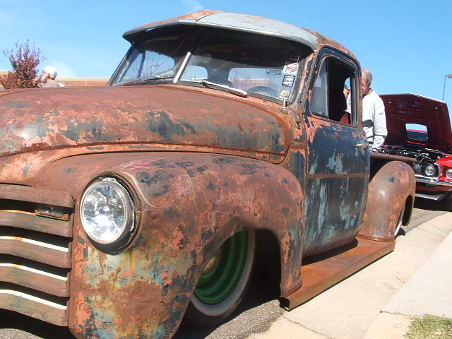 Rusty pickup truck with green wheels and a visor