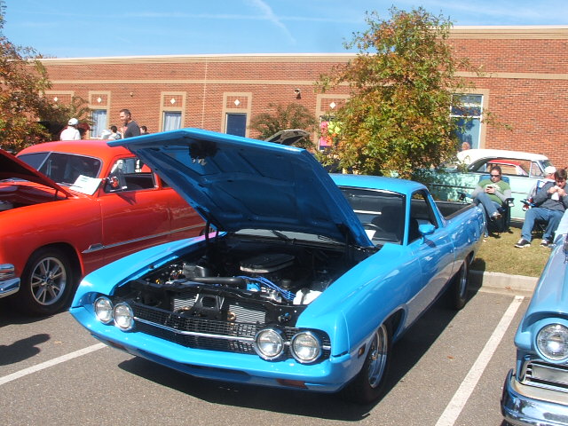 Blue pickup truck with hood open, showing engine. Front view