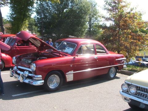 1971 Ford Ranchero - Red sedan parked at an outdoor event, hood is open showing the engine bay.