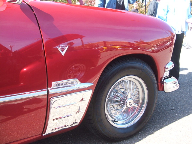 Red car fender with chrome trim and wire wheel, visible 'Ranchero' script
