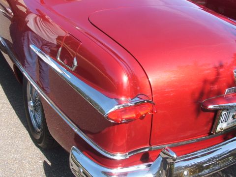 1971 Ford Ranchero - Close-up of a vintage red car's rear end, showing chrome accents and a tail light assembly.