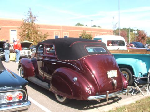 1971 Ford Ranchero - A classic maroon convertible sedan with a black top is parked at an outdoor event, with other vehicles visible.