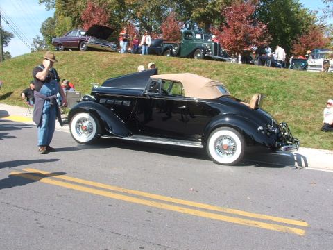 1971 Ford Ranchero - A classic black convertible is displayed at an outdoor event with other vehicles and spectators present.