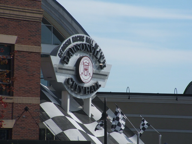 Georgia Racing Hall of Fame Dawsonville City Hall sign with checkered flag motif and flags
