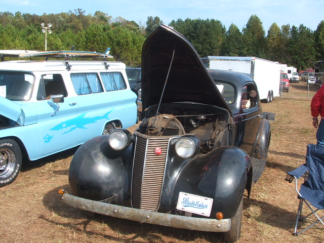 Black vintage car with hood open, showing engine. License plate reads "Studebaker"