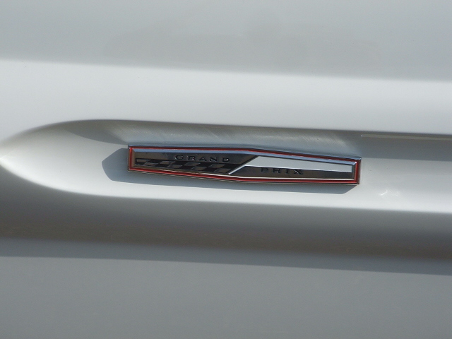 White car fender with a chrome and red 'Grand Prix' emblem