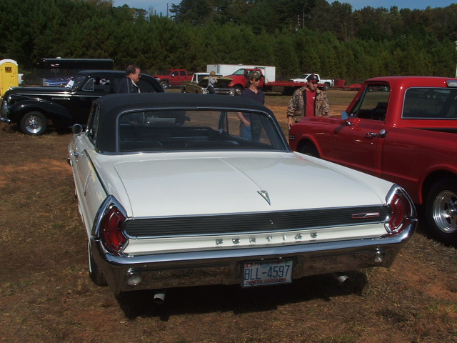 White convertible with black top, rear view, Pontiac badging