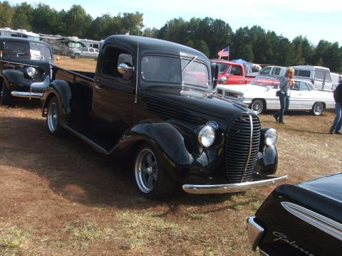 1971 Ford Ranchero - A black 1937 Ford pickup truck is displayed at an outdoor event, parked alongside other vehicles.